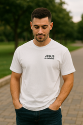 Man wearing a white t-shirt with 'Jesus is my commander' text outdoors.
